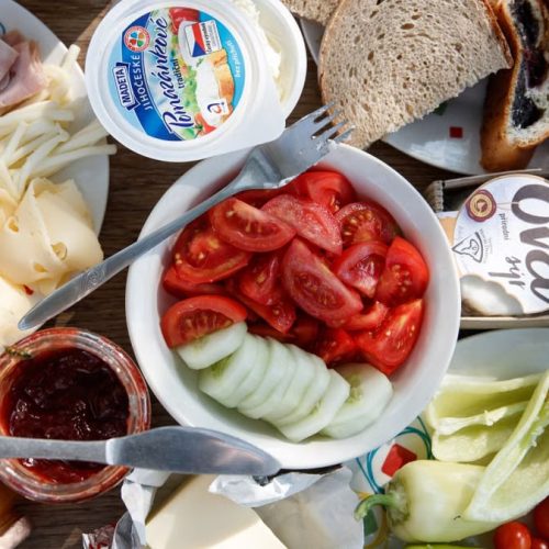 Delicious breakfast setup with cheese, cold cuts, bread, and fresh vegetables.