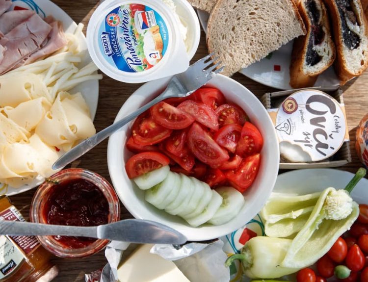 Delicious breakfast setup with cheese, cold cuts, bread, and fresh vegetables.