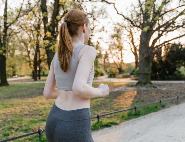 A woman jogs in a park during sunset, enjoying an outdoor fitness routine.