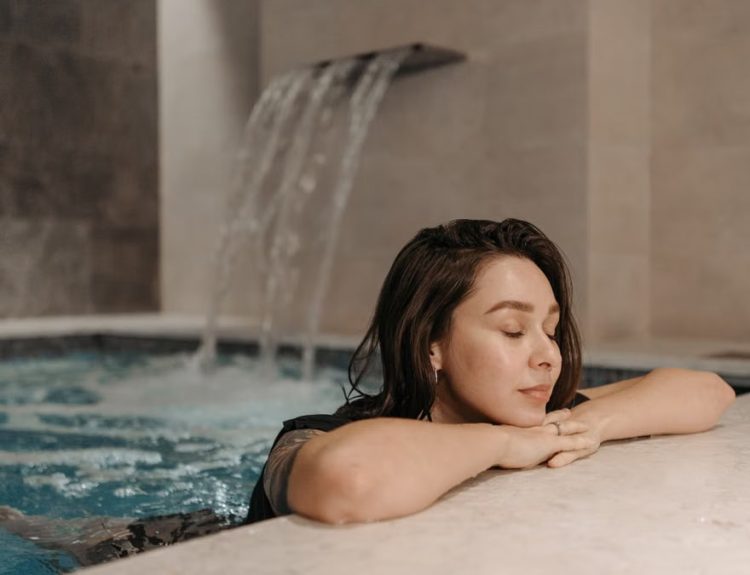 Caucasian woman enjoying a calm moment in an indoor swimming pool spa setting.