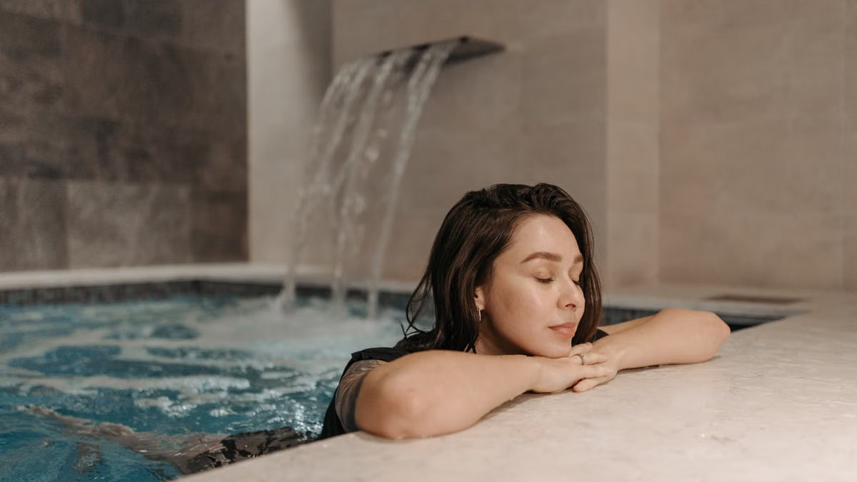 Caucasian woman enjoying a calm moment in an indoor swimming pool spa setting.